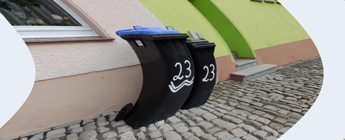 Foto: verzerrte Abfallbehälter vor grünem Haus in Eisleben